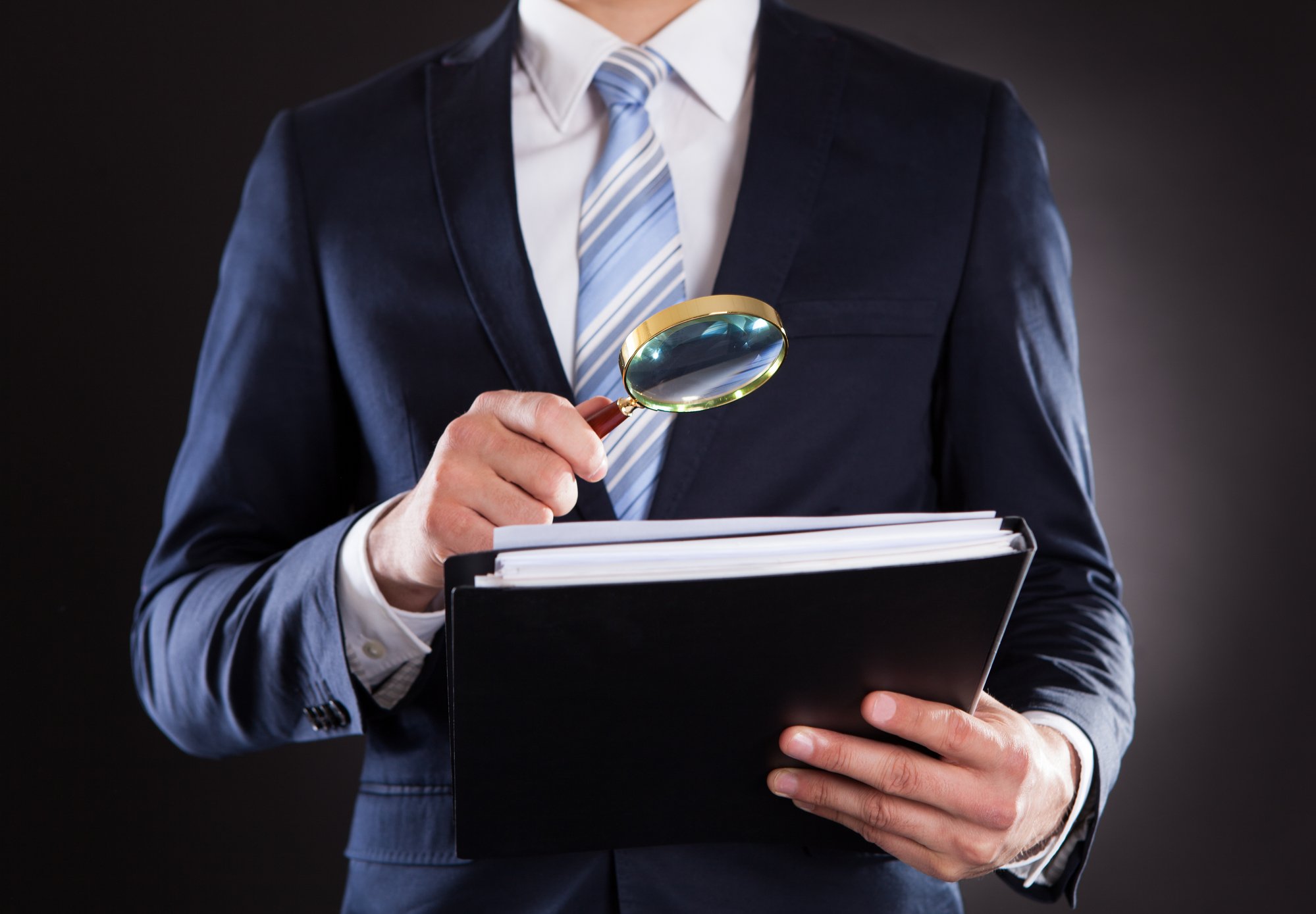 Businessman Examining Documents With Magnifying Glass