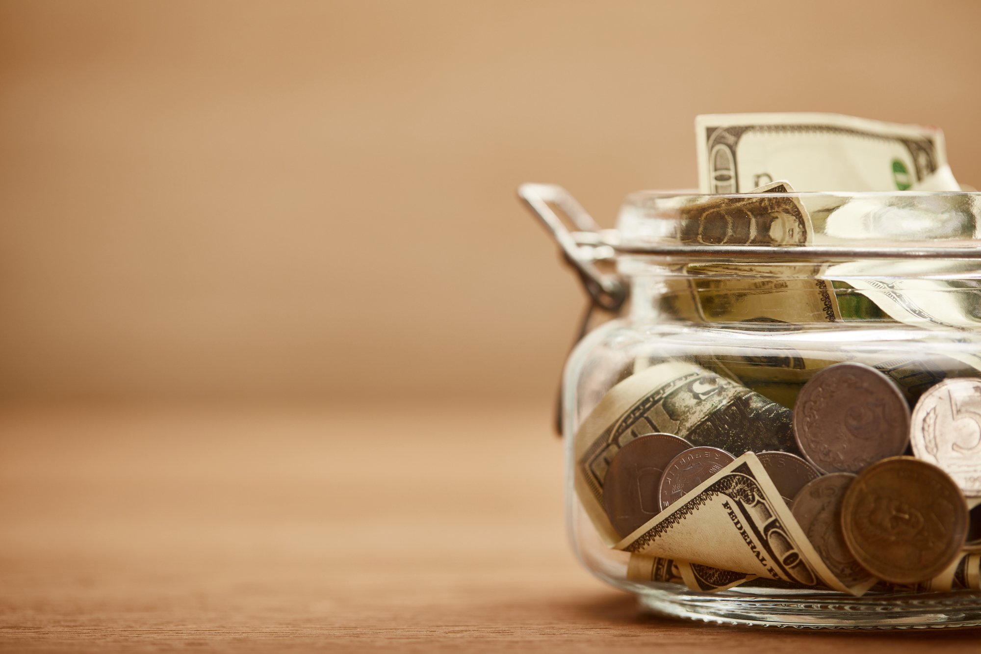 Close up view of glass jar with dollar banknotes and metal coins