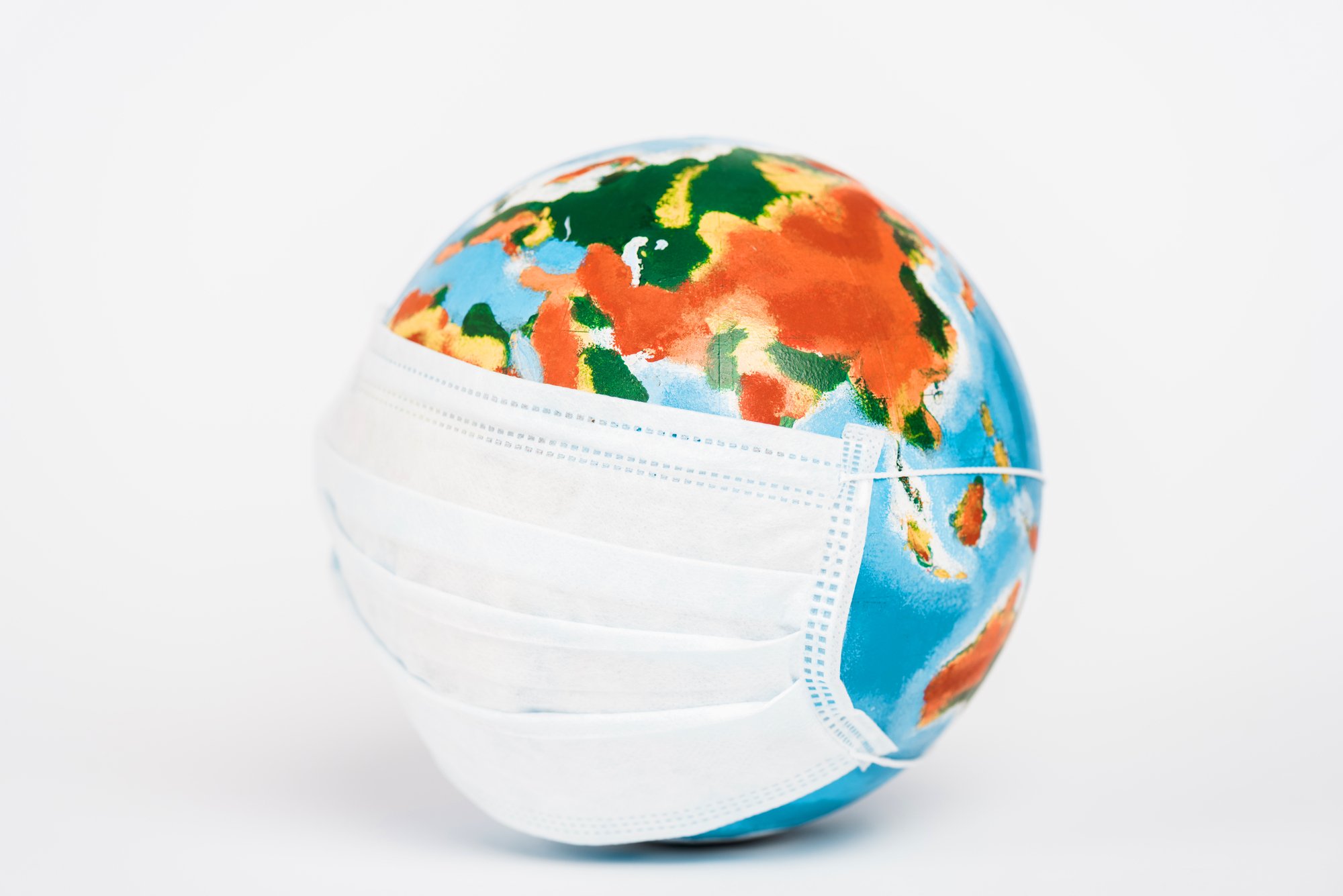 Colorful globe in medical mask on white