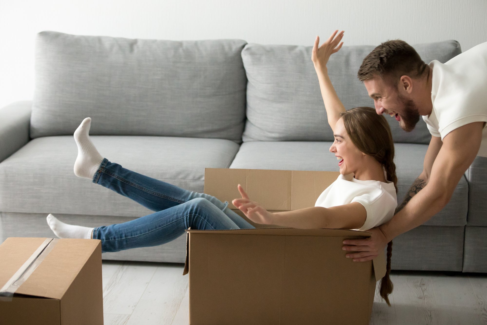 Happy couple riding in boxes having fun unpacking boxes