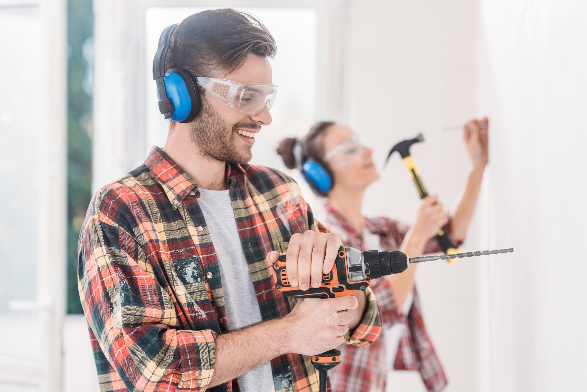 Happy young man using electric drill during house repairment