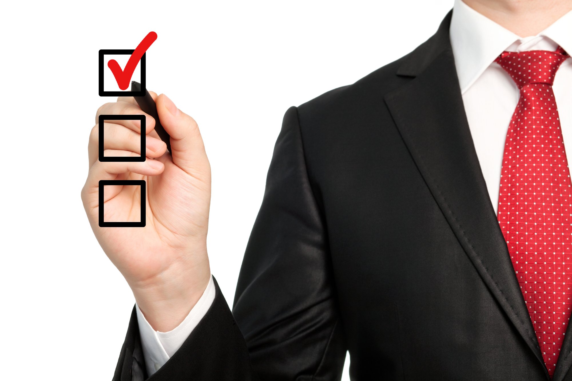 Isolated businessman in a suit holding a pen and writing red check