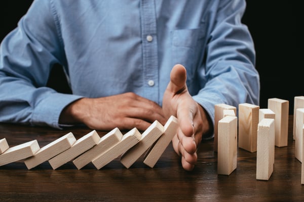 Partial view of man preventing wooden blocks from falling on desk