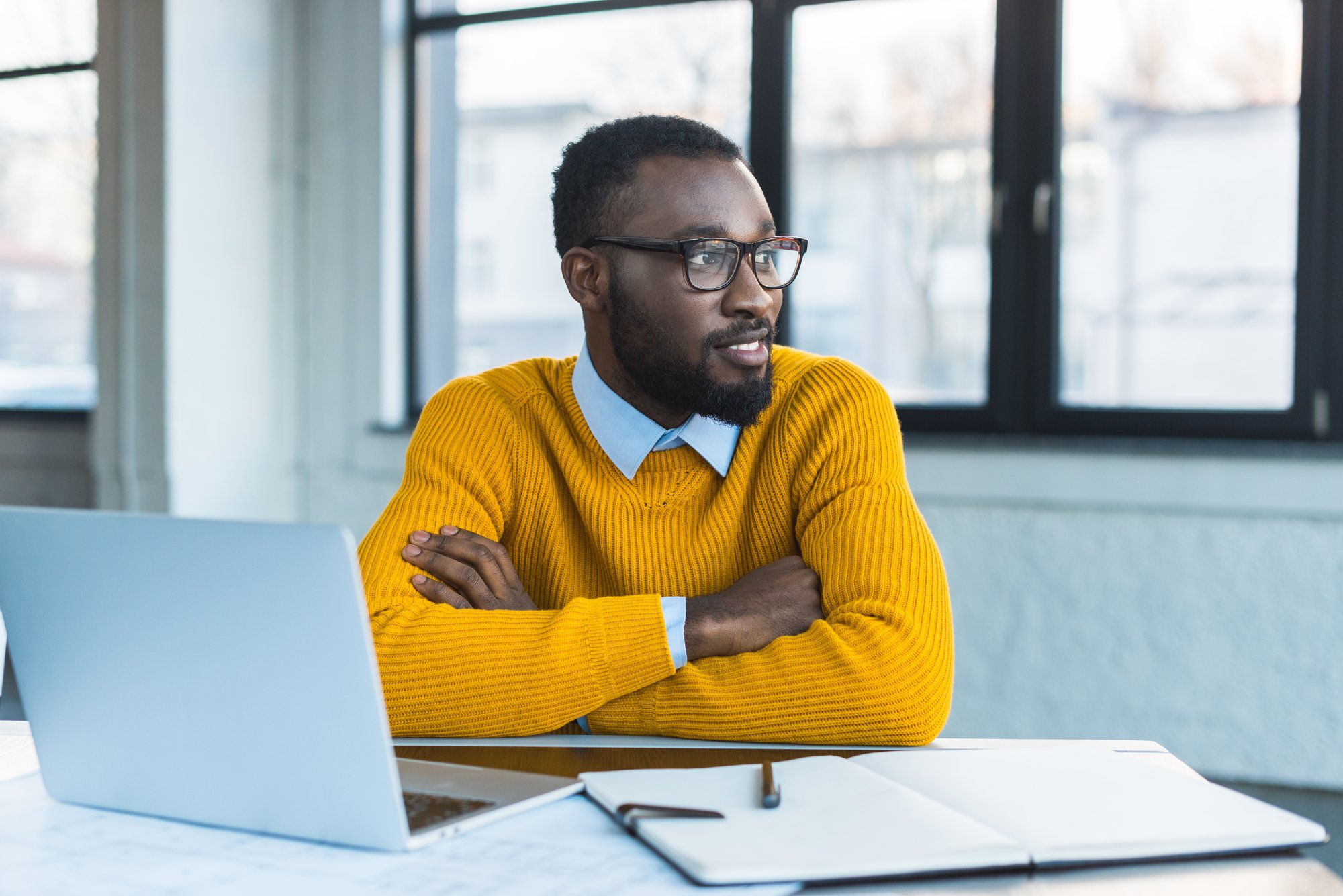 Smiling african american businessman with crossed arms in office