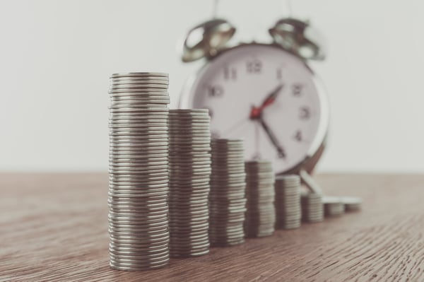 Stacks of coins and alarm clock on tabletop, saving concept