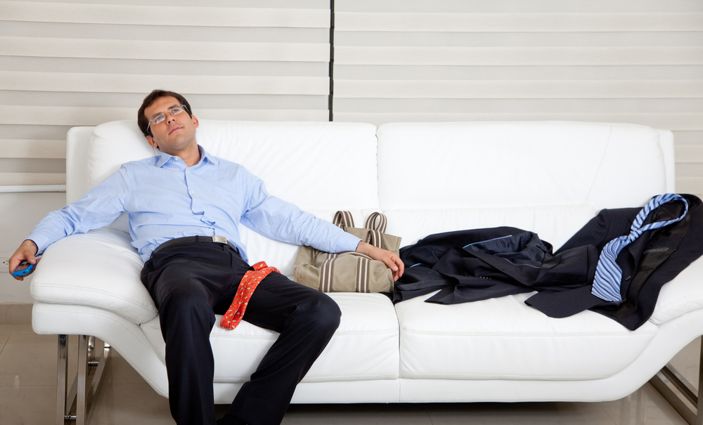 Exhausted business man lying on the sofa with a mess