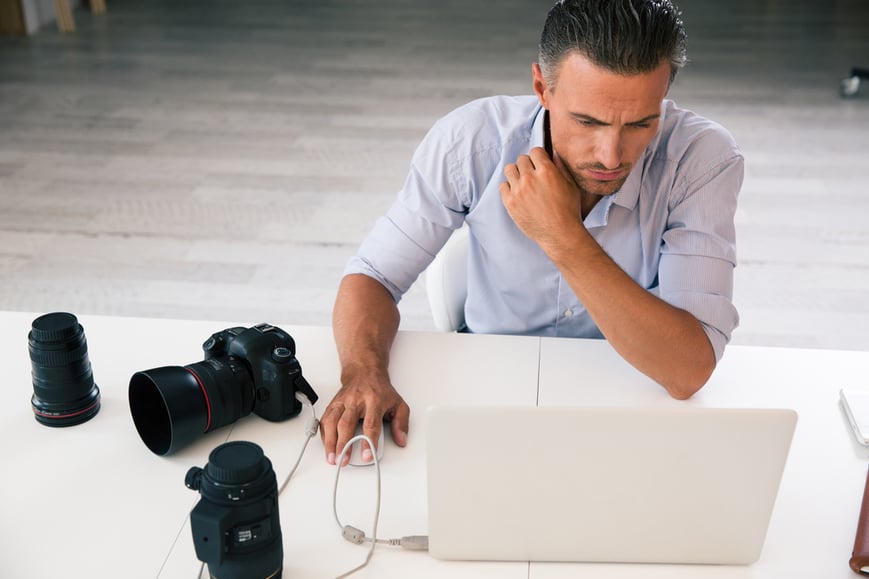 Portrait of a photographer using laptop at his workplace