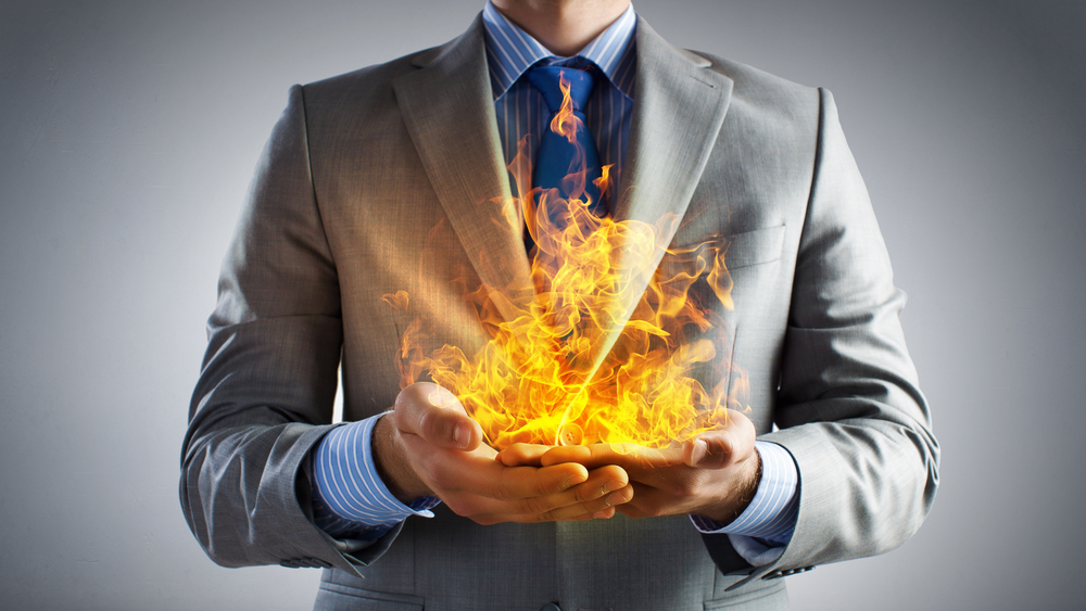 Young businessman holding fire flames in palms