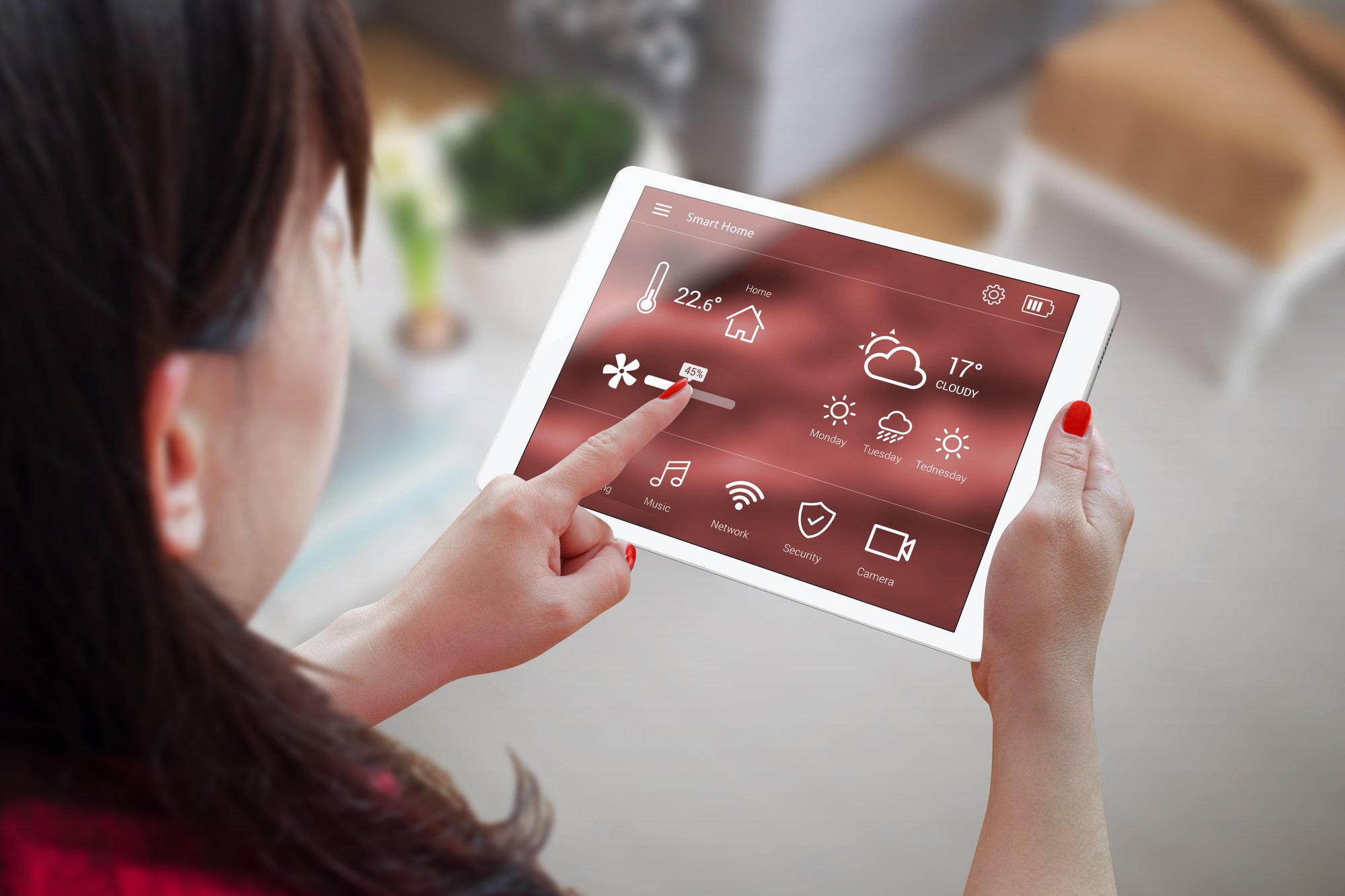 Woman use application for smart home control on tablet. Interior of living room in the background