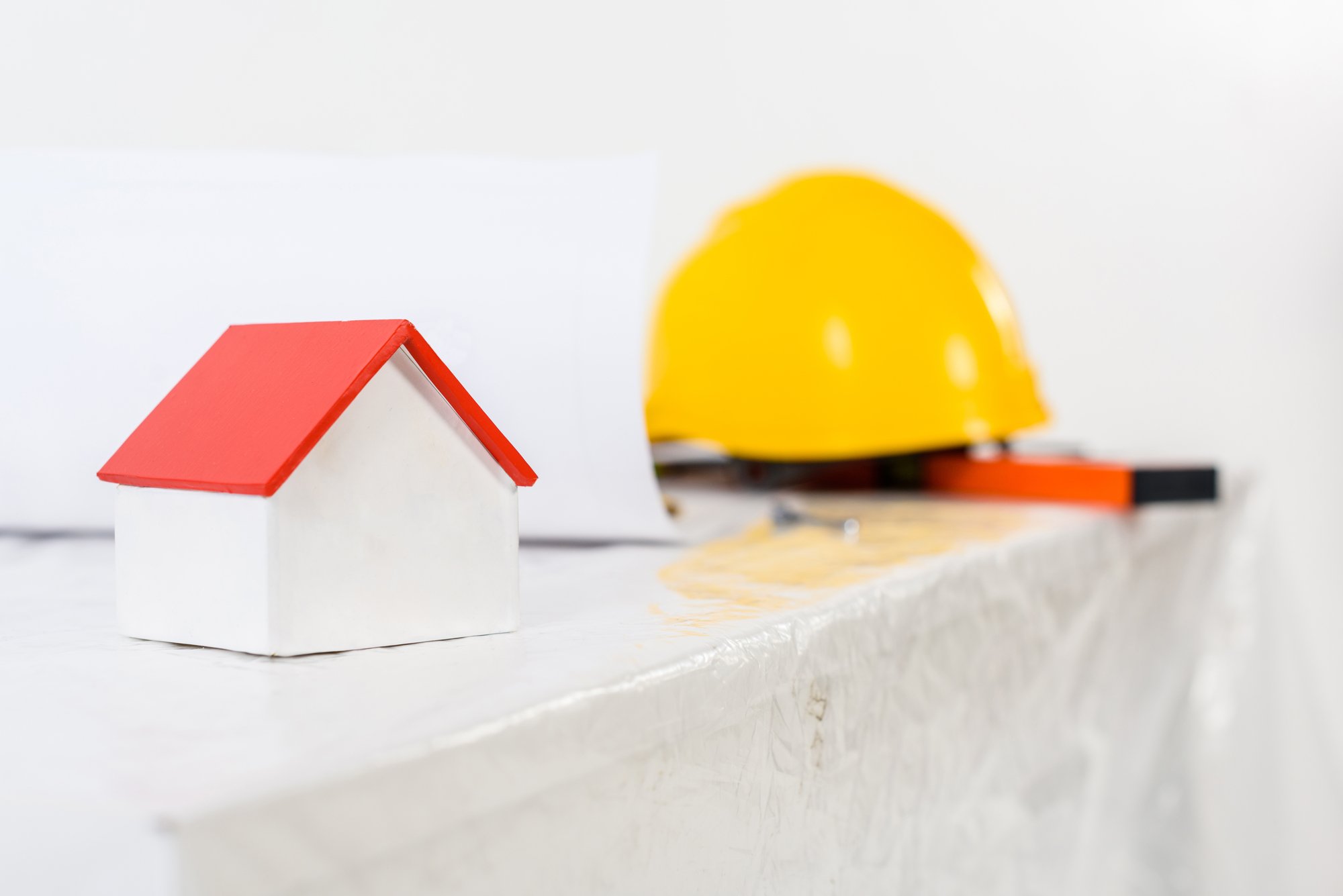 Yellow helmet and small house on table