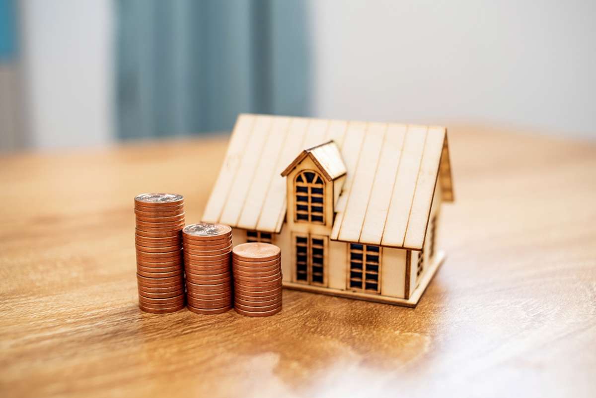a row of coins and a small house model on the desk
