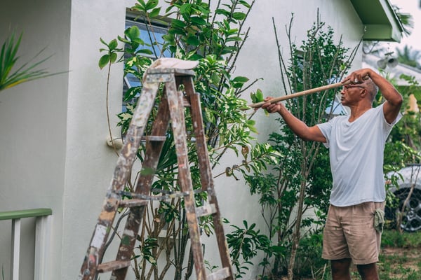 man painting wall outside a house