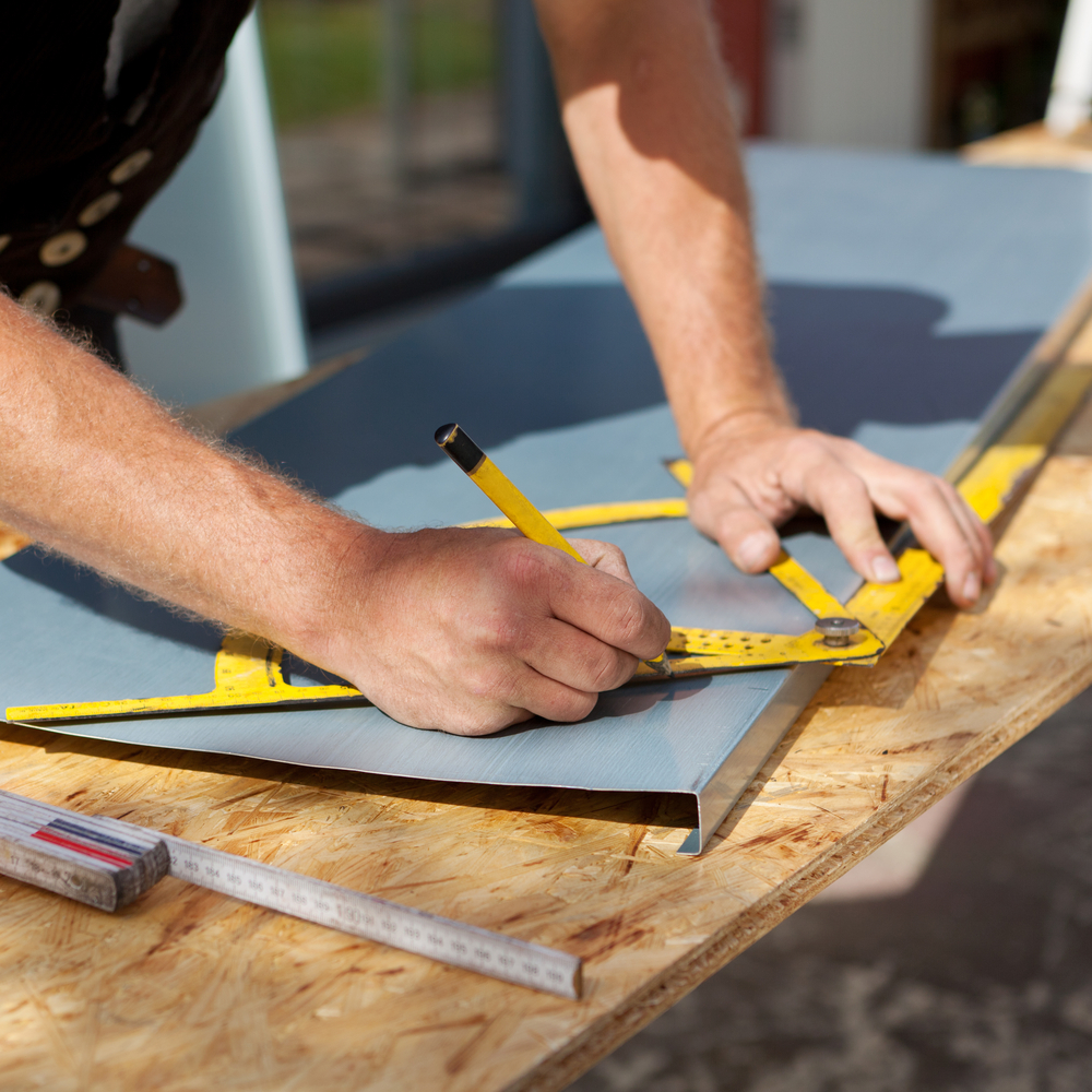 Roofer working with a protractor to make markings on a metal sheet