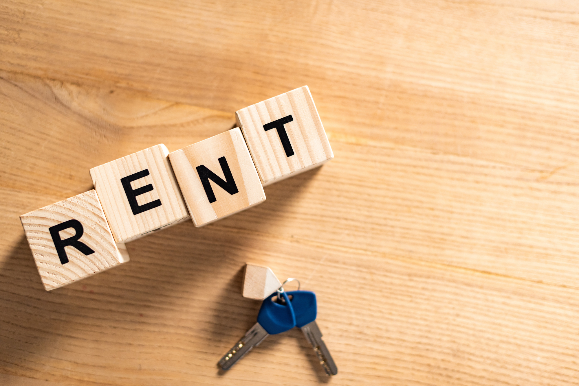 Top view of keys with key chain near wooden cubes with rent lettering on table